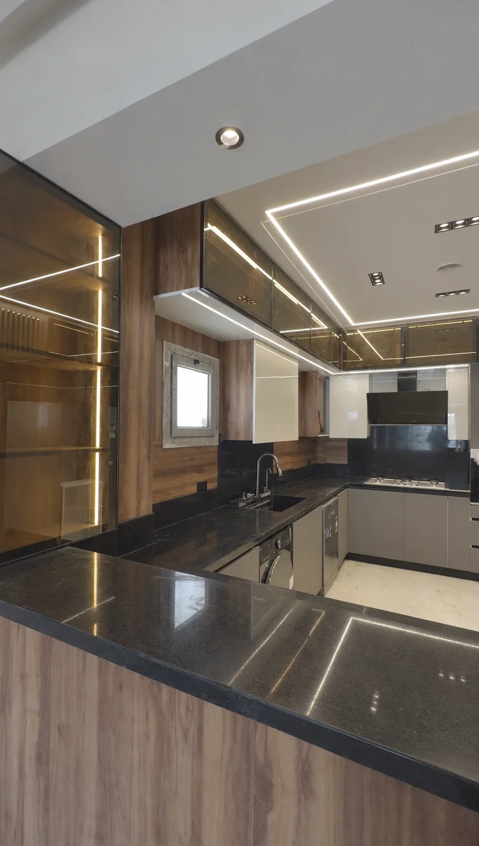 A corner of the kitchen counter in dark stone, with light lines in the ceiling and cabinets.