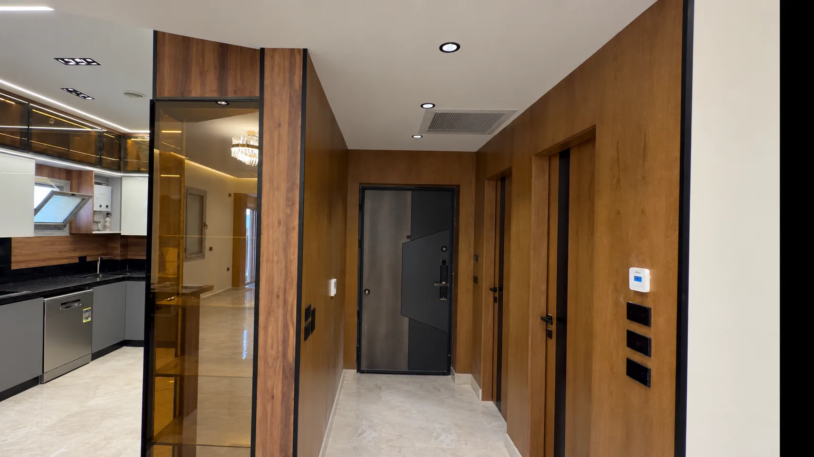 A wood-panelled hall leading to the front door, with the kitchen and a glass display cabinet on the left.