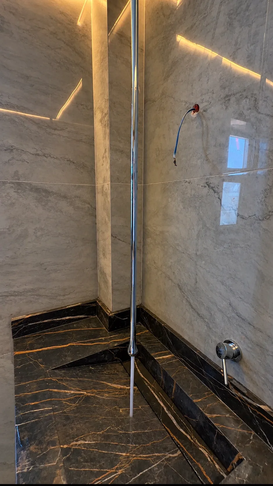 The same shower area: the dark veined stone floor and the light walls.